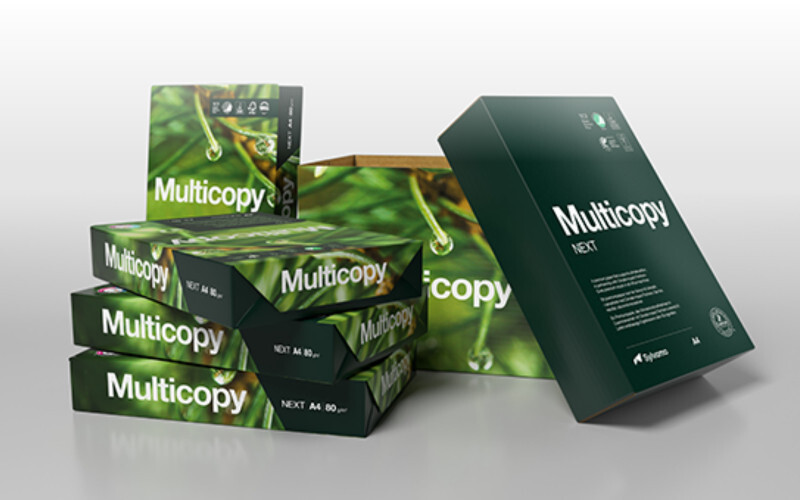 Työpöydällä Multicopy kopiopapeririisi, kahvikuppi, kynä ja muita toimistotarvikkeita.