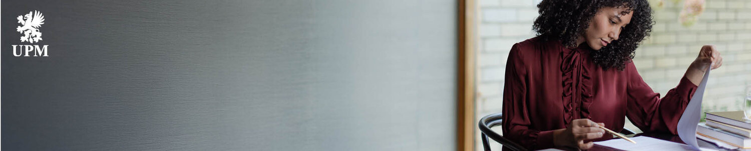 Nainen kirjoittaa valkotaululle ja hymyilee.