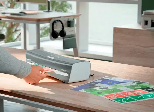 Käsi ojentuu Leitz iLAM -laminointikonetta kohti.